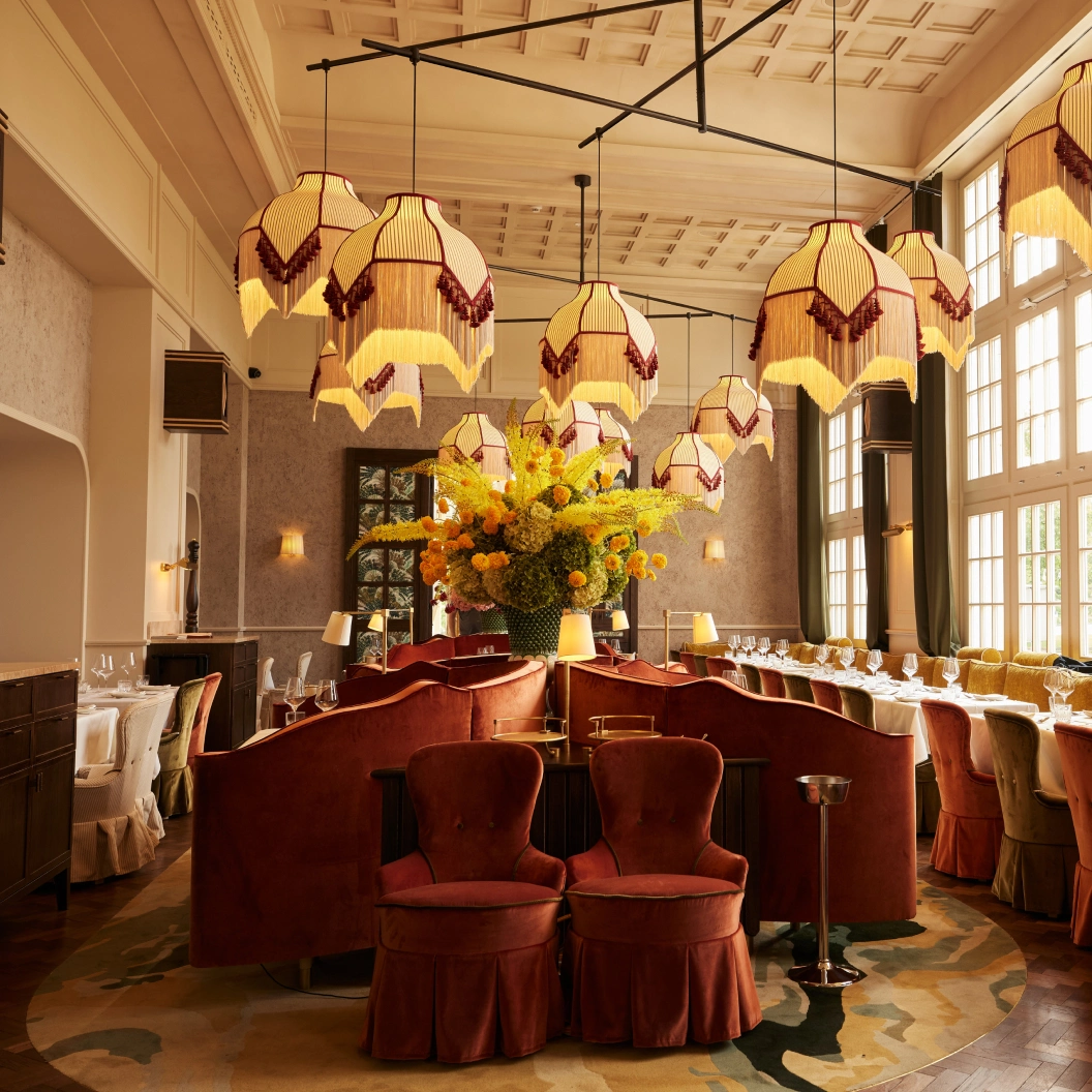 Grosser Gastraum des Restaurant Pellicano München mit Blumenarrangement und Kronleuchtern