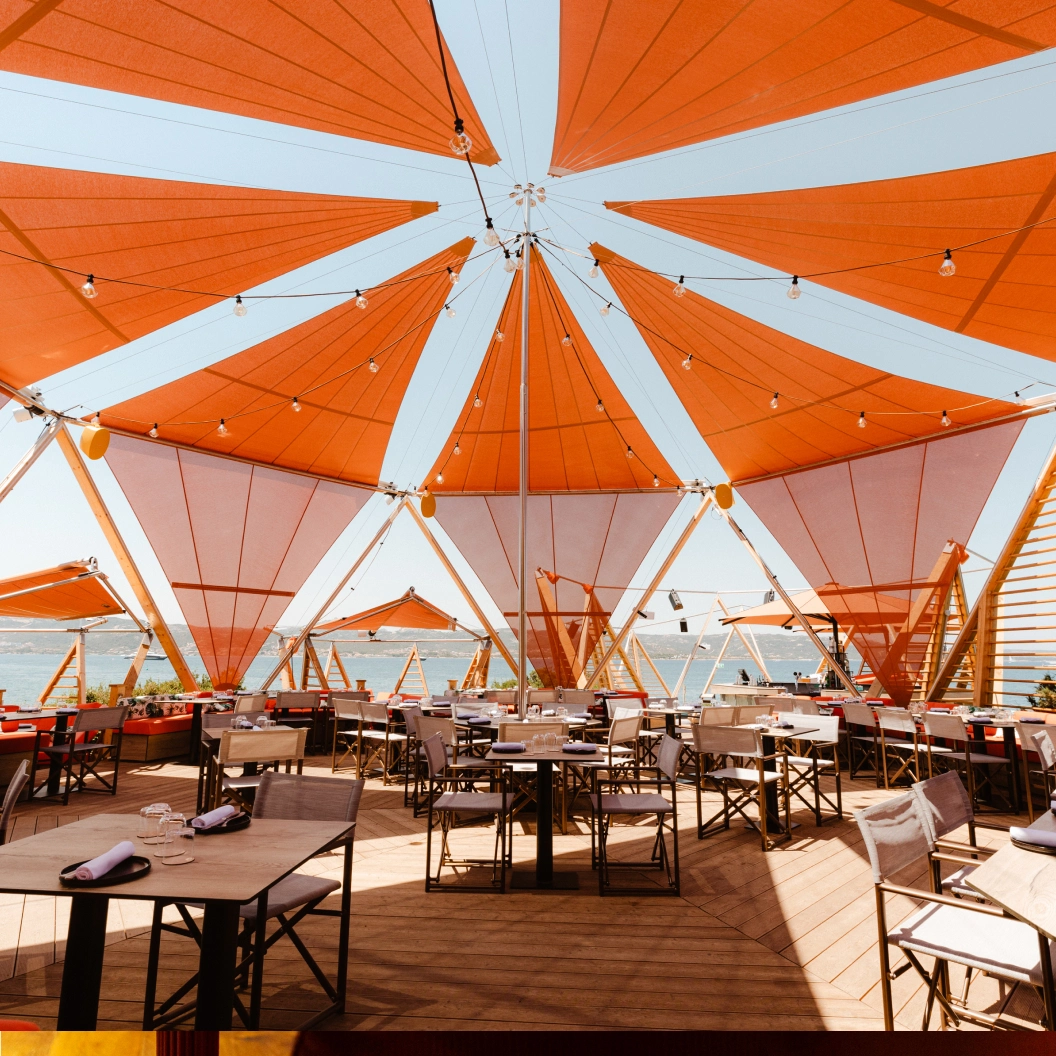 Referenzprojekt Tasteful Hospitality – Aussenbereich mit orangefarbenen Sonnensegeln