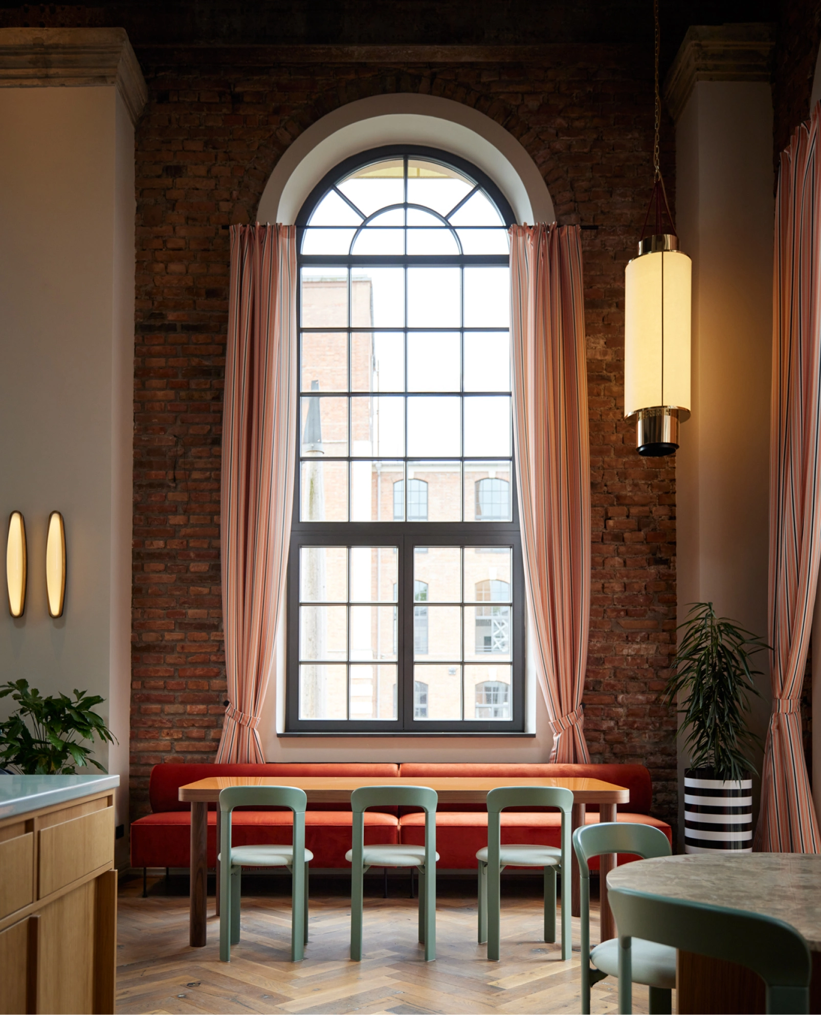 Industrieller Innenraum der Brasserie Turbinenhaus München mit Backsteinwänden und Bogenfenstern